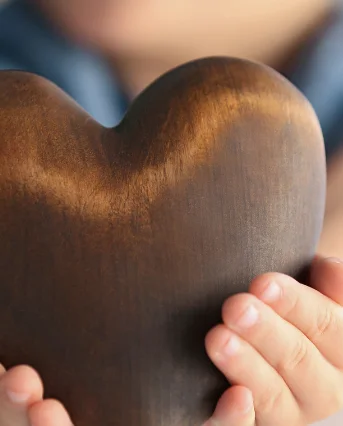 Kinderhanden houden een houten hart vast